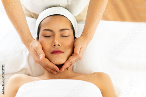 Massage Health & Wellness concept. Beauty treatment concept beautiful Asian Thai woman liing on bed for facial and head massage spa treatment by Masseur. relaxing with closed eyes towel on head