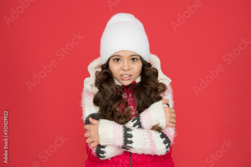 its cold outside. winter outfit for kids. happy childhood. frozen child in knitted hat. feeling cosy in warm clothes. winter fashion. portrait of pure beauty. small girl long curly hair