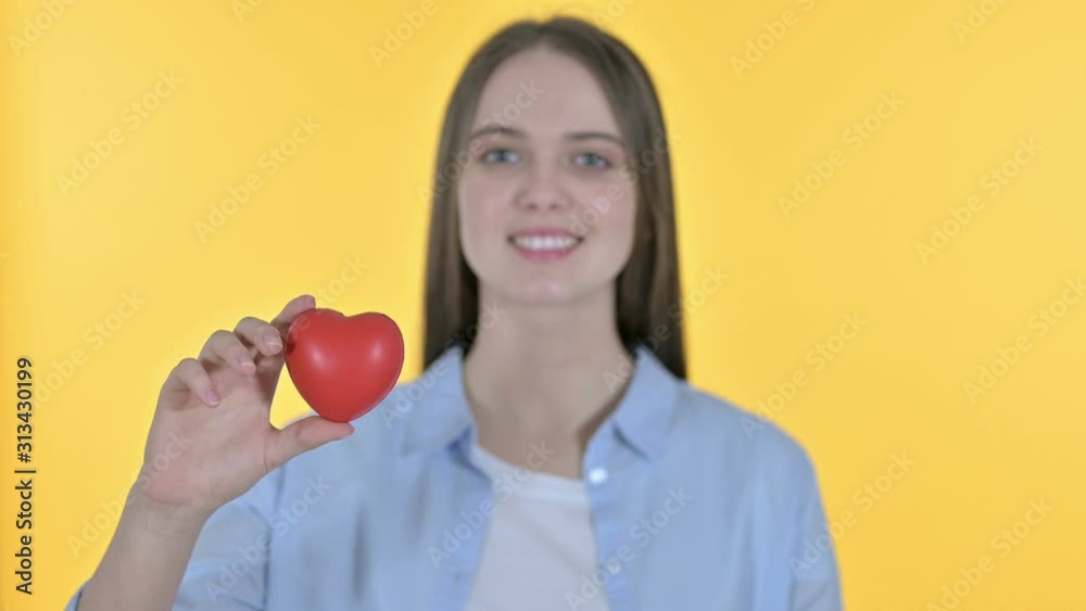 Young Woman holding Red Heart Shape, Yellow Background Young Woman holding Red Heart Shape, Yellow Background