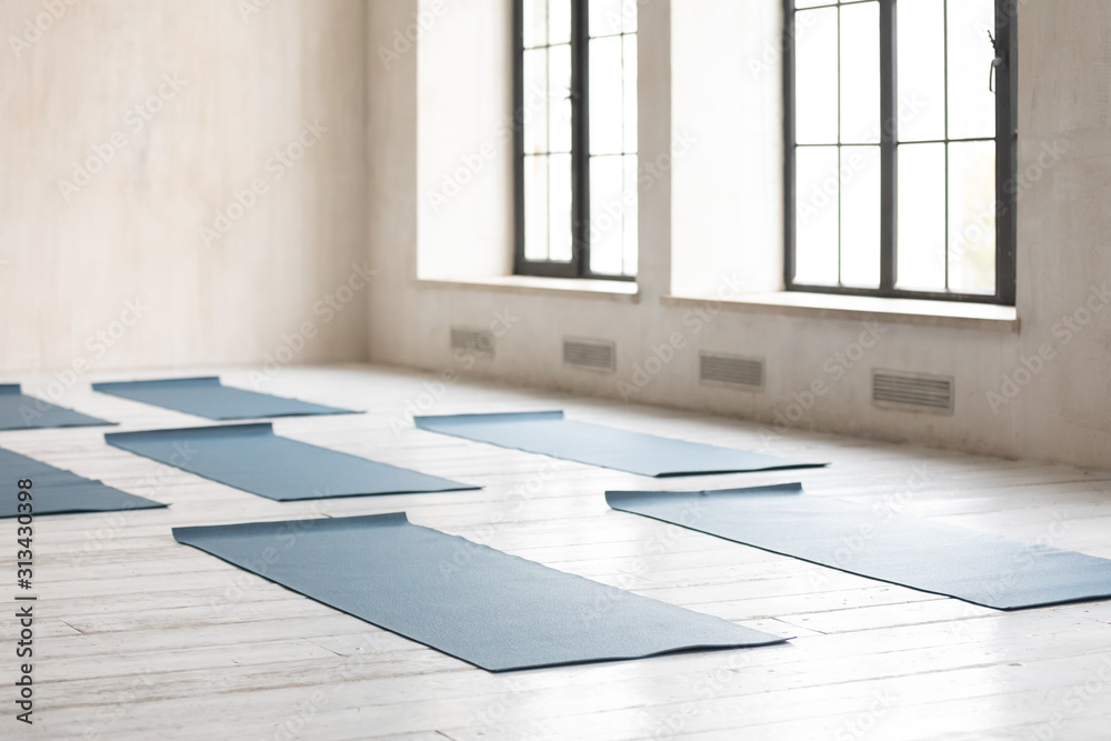 Unrolled yoga mats on wooden floor in empty fitness center - obrazy, fototapety, plakaty 