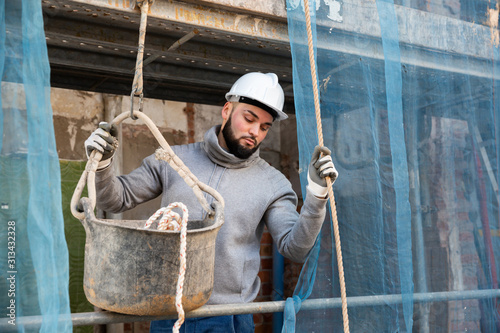 Guy lowering down bucket on rope