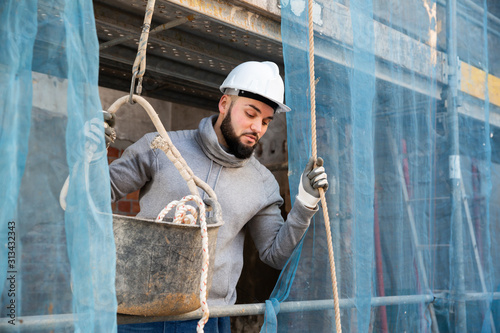 Guy lowering down bucket on rope