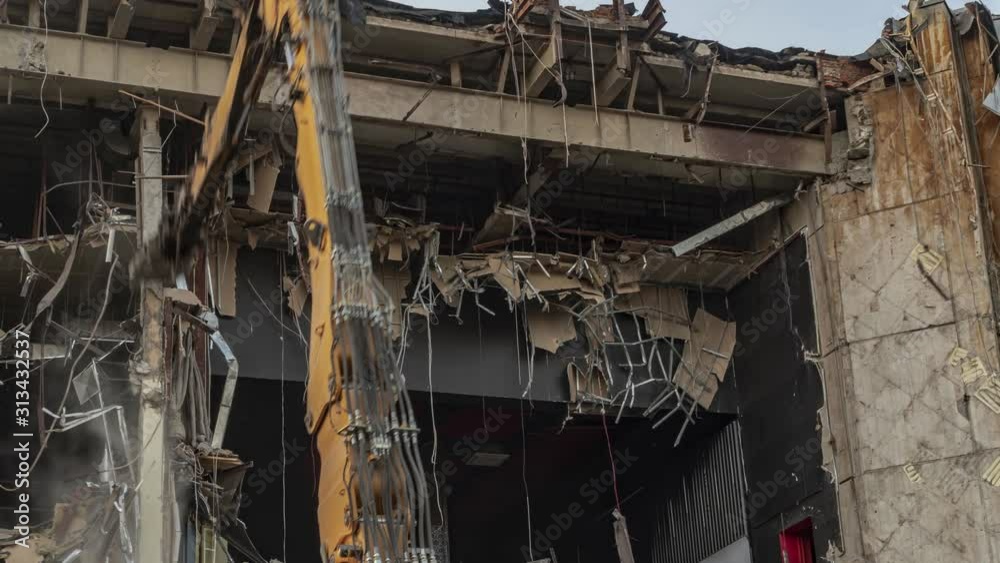Destruction of the cinema building on a steel frame with a machine with hydraulic scissors, time lapse