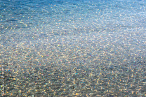 Crstal clear water of the adriatic sea  beach shot. Small white and blue waves on a rocky pebble beach
