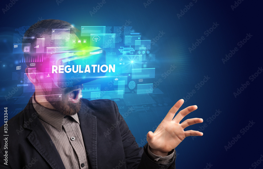 Obraz premium Businessman looking through Virtual Reality glasses with REGULATION inscription, innovative security concept