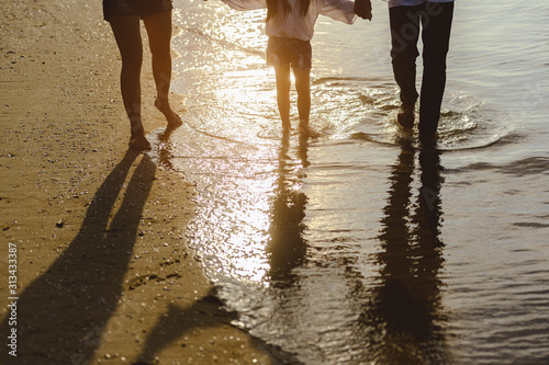 Family, travel, beach, relax, lifestyle, holiday concept. Family who enjoy a picnic. Parents are holding hands their children and walking on the beach at sunset in holiday. © Day Of Victory Stu.
