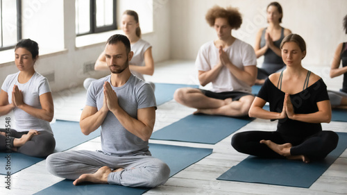 Group of diverse young people practicing yoga, doing Padmasana exercise © fizkes