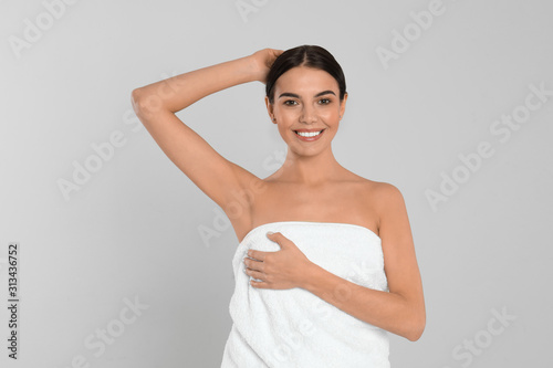 Young woman showing hairless armpit after epilation procedure on light grey background