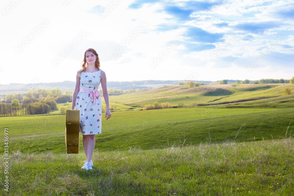 Woman walking in green field with acoustic Guitar Woman walking in green field with acoustic Guitar