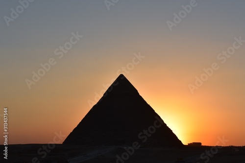 sunset behind khafre pyramid shiloutte pyramid with orange light © decha