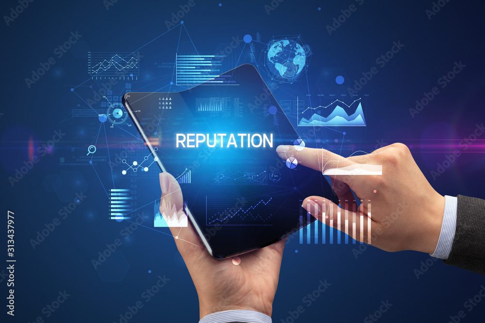 Businessman holding a foldable smartphone with REPUTATION inscription, successful business concept Businessman holding a foldable smartphone with REPUTATION inscription, successful business concept