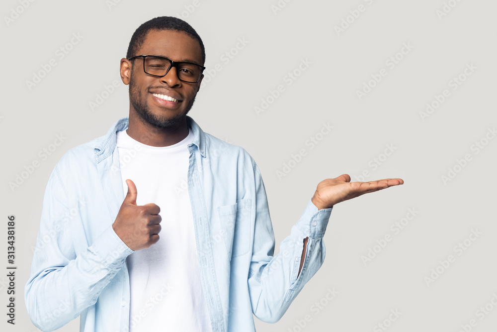 Attractive african guy showing open palm and thumbs up gesture Attractive african guy showing open palm and thumbs up gesture