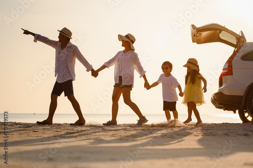 Family, travel, beach, relax, lifestyle, holiday concept. Family who enjoy a picnic. Parents are holding hands their children and walking on the beach at sunset in holiday.