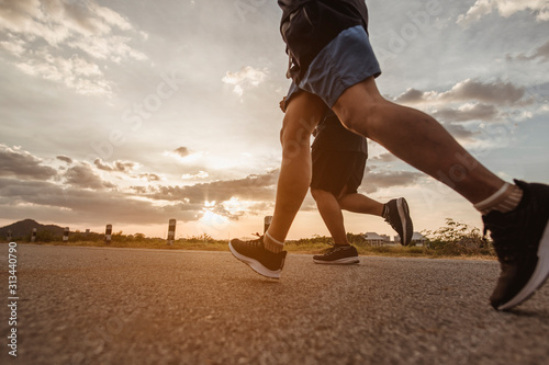 fitness, workout, jogging, exercise, lifestyle and healthy concept. The man is jogging to exercise for his health on the edge of the roadside the sunset.