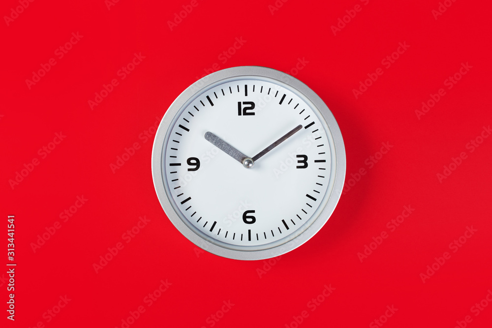 White wall clock with a yellow used hanging on the wall. Minimalist image of a wall clock on a red background with copy space White wall clock with a yellow used hanging on the wall. Minimalist image of a wall clock on a red background with copy space