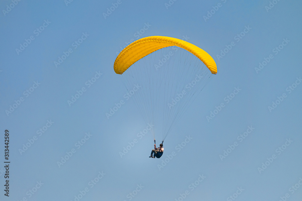 Flight on a yellow paraglider in blue sky Flight on a yellow paraglider in blue sky