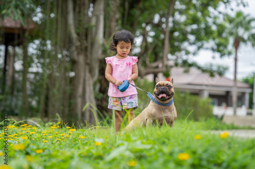 Cute little girl during morning walk with french bulldog.