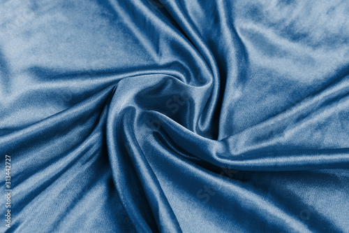 Shining classic blue silk atlas satin fabric with folds, fabric waves. Real fabric background. Color of the year 2020