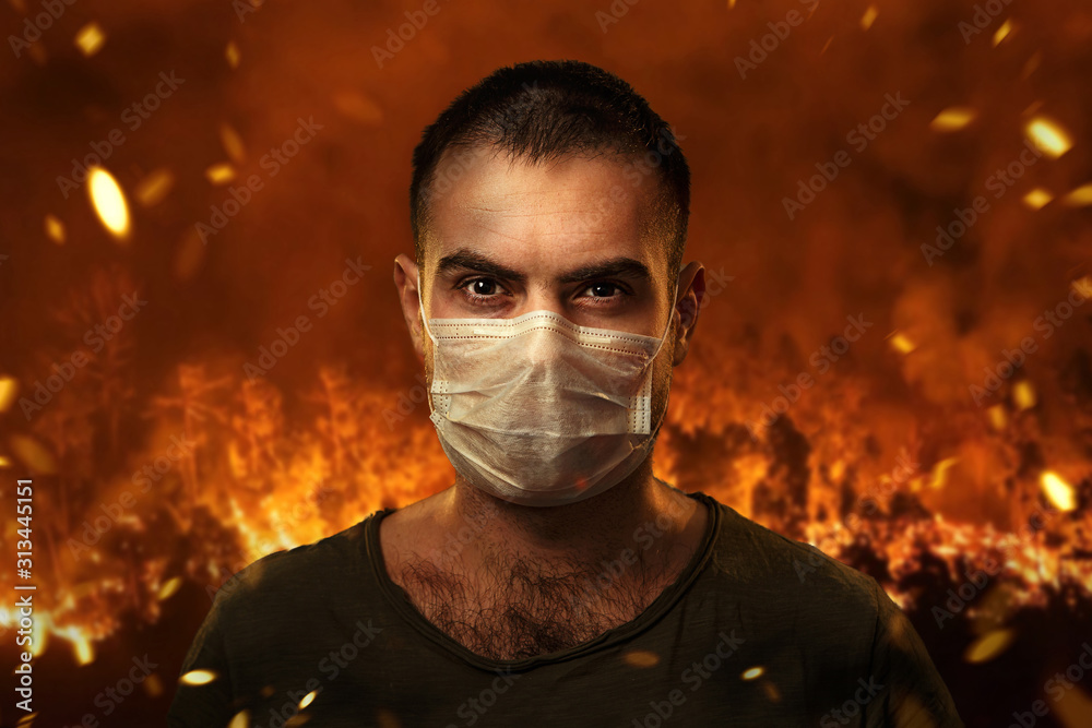 A man in a medical mask to protect the cuts of breath against the backdrop of severe forest fires. The concept of fires in Australia.