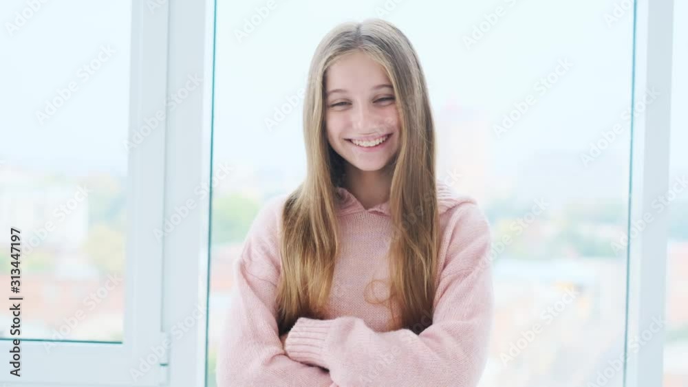 Laughing cute girl with arms crossed in front of window Laughing cute girl with arms crossed in front of window