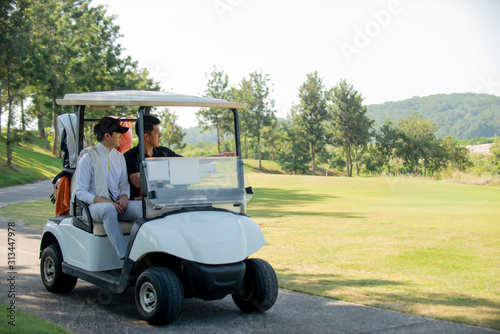 Two asian golfer sitting in car golf with golf clup survey golf course