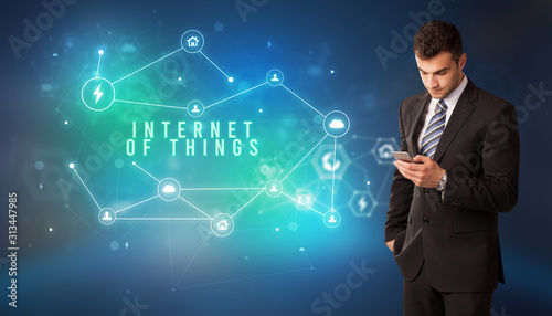 Businessman in front of cloud service icons with INTERNET OF THINGS inscription  modern technology concept