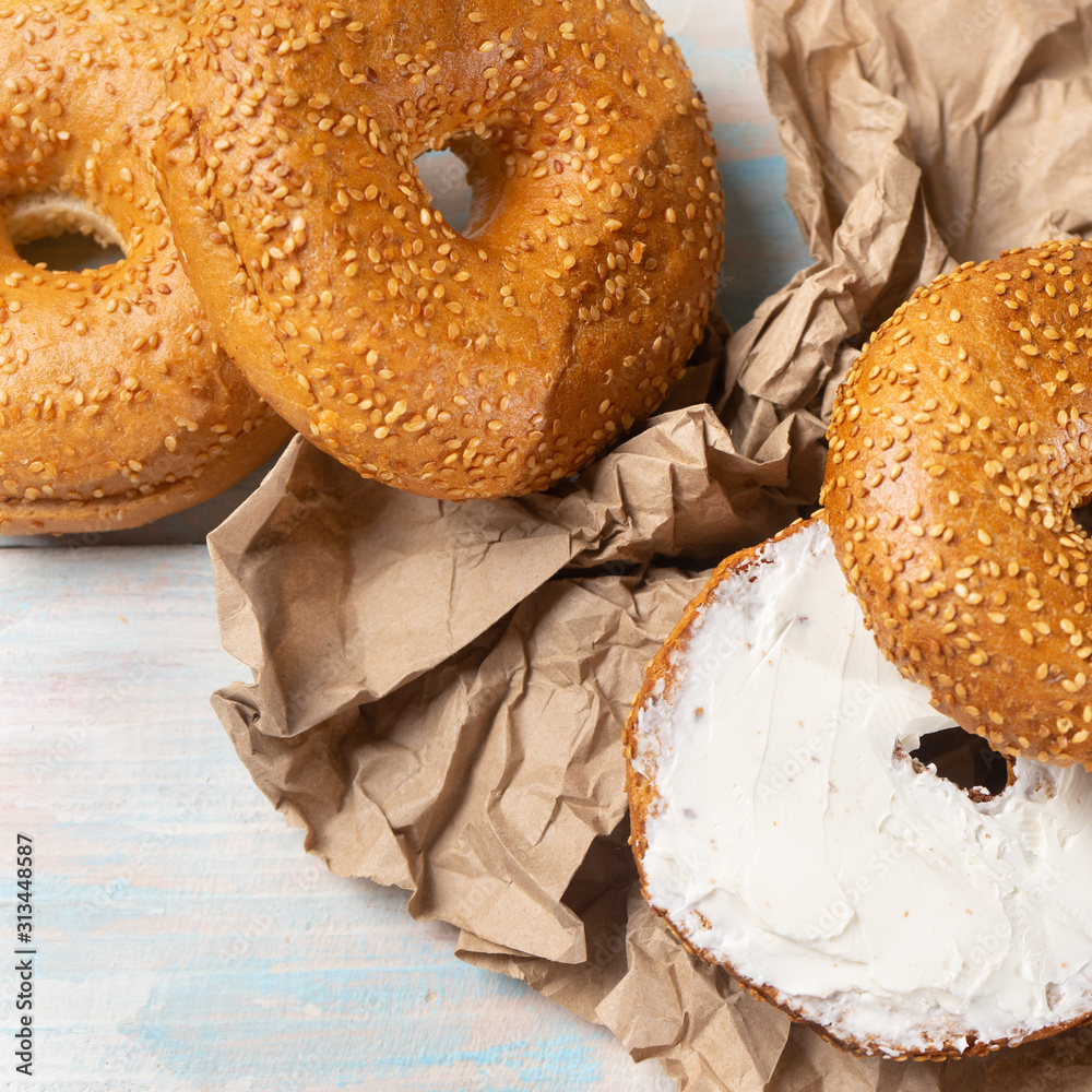 Sesame bagels with spreadable cream cheese on colorful background
