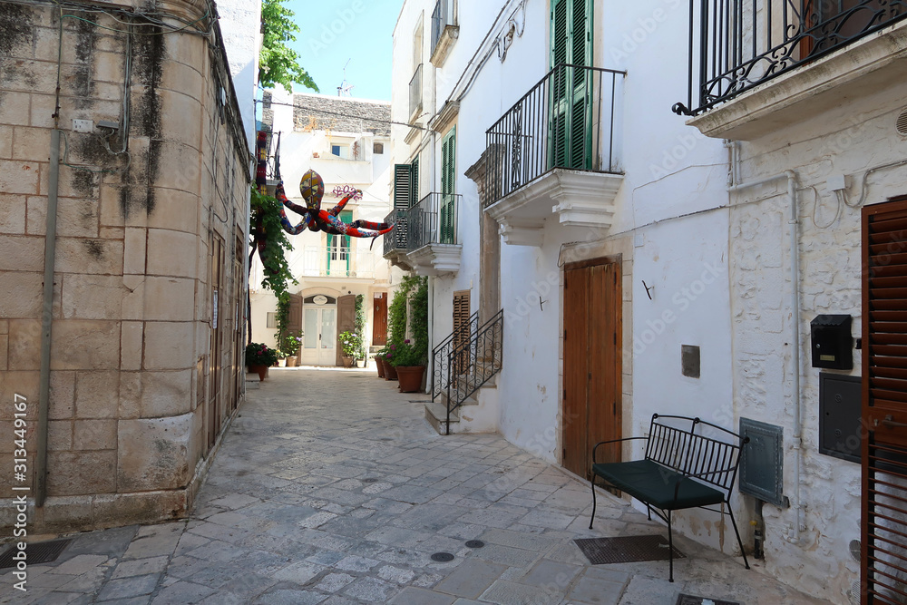 Fototapeta premium Street in Locorotondo town, Italy, region of Apulia, Adriatic Sea - colorful fabric octopus hanging above the street