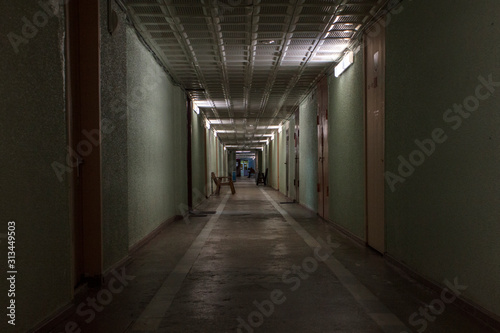 long corridor with wooden doors and a sitting silhouette at the end