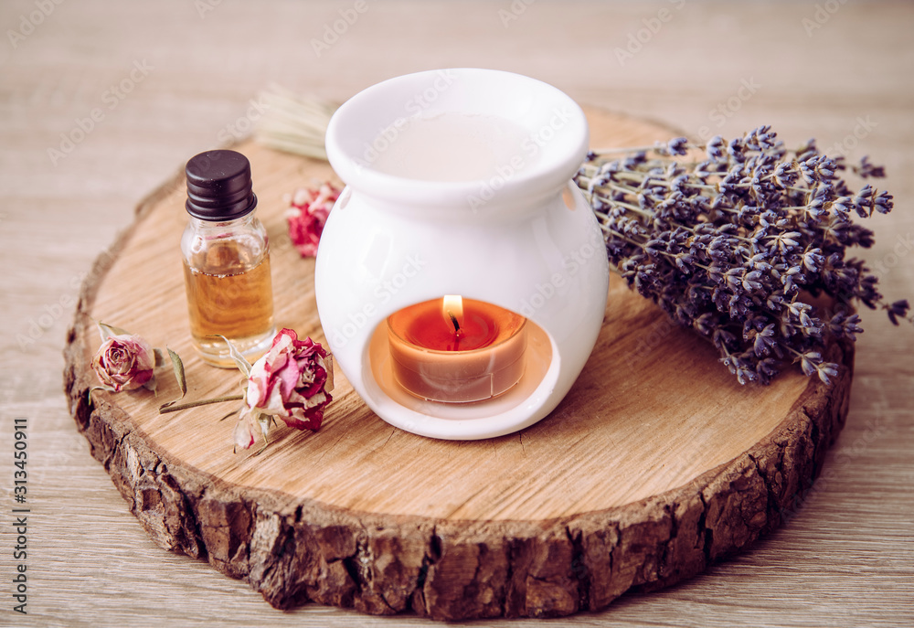 Vintage style picture of white ceramic candle aroma oil lamp with essential  oil bottle and dry flower petals on natural pine wood disc, dry background  with copy space. Photos | Adobe Stock