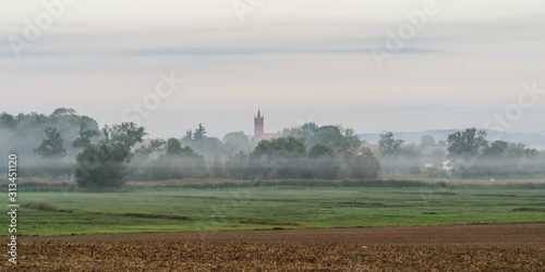 Scenic view of a village in mist against a cloudy sky 