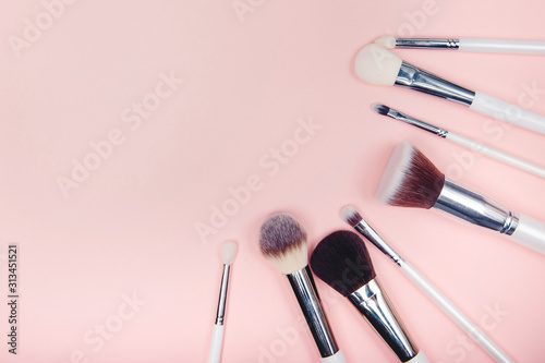 Set makeup brushes on pink color background. Top view point, flat lay photo