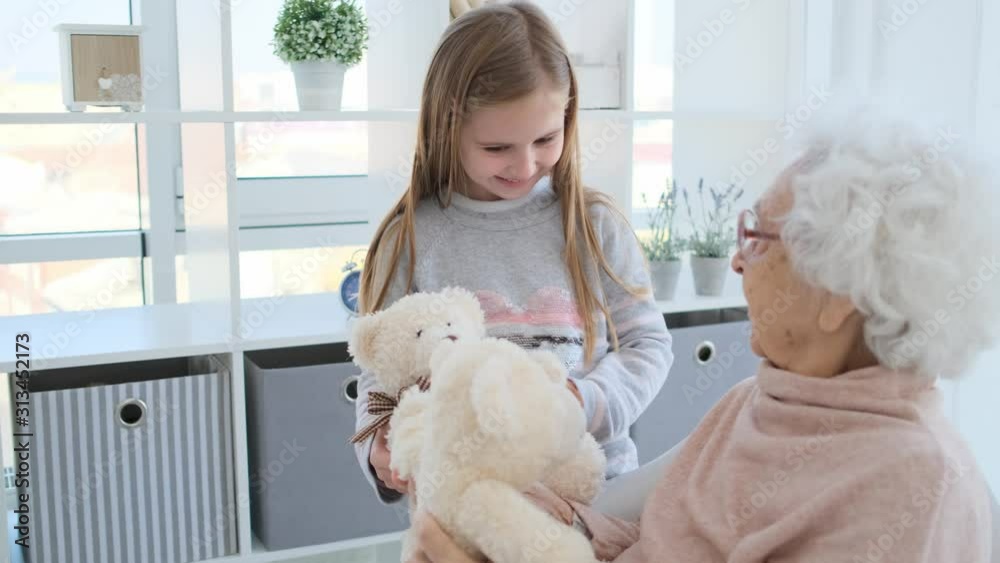 Smiling granny playing plush bears with granddaughter indoors Smiling granny playing plush bears with granddaughter indoors