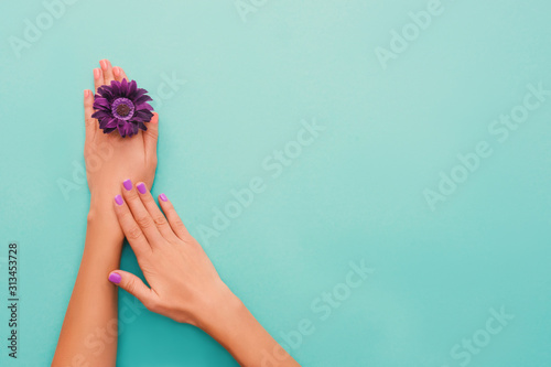 Stylish coral purple nails on turquoise background.