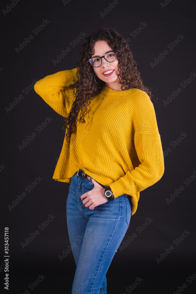 Foto Stock Young girl model posing with yellow t-shirt and blue pants in  black background | Adobe Stock