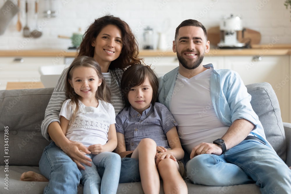 Happy family with kids seated on couch posing for camera Happy family with kids seated on couch posing for camera