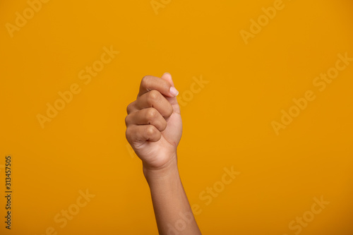 Woman hand holding something on yellow background, closeup of hand. photo
