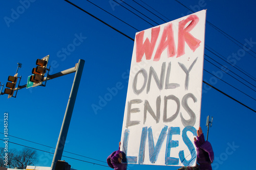 Protester holding up hand made sign saying War Only Ends Lives at outdoor rally
