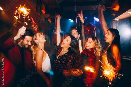 Group of friends having fun and holding sparklers at New Year's party