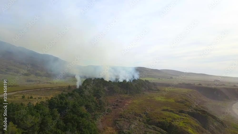 Aerial, rising, drone shot tilting towards smoke and burning forest, Californian wildfire, at cloudy day, in Big sur, California, USA Aerial, rising, drone shot tilting towards smoke and burning forest, Californian wildfire, at cloudy day, in Big sur, California, USA