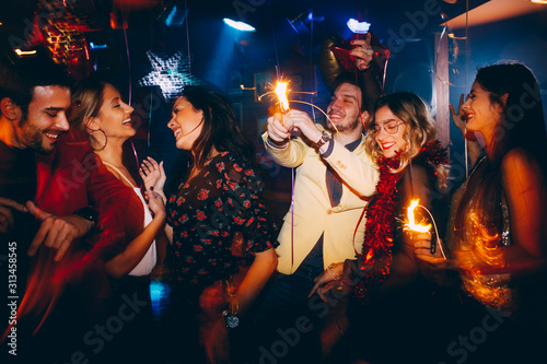 Group of friends having fun and holding sparklers at New Year's party