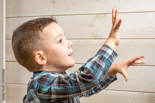 Bild auf Leinwand A 4 years old boy in a blue clerical shirt is crying on a light wooden background