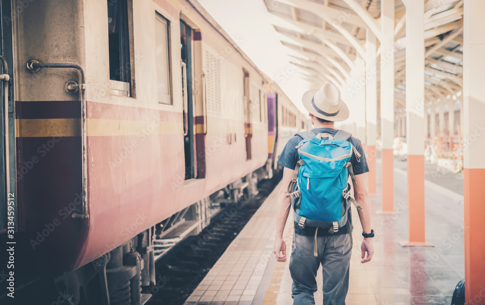 An Asian man, a backpack and a hat at the train station with travelers. Tourism concept An Asian man, a backpack and a hat at the train station with travelers. Tourism concept