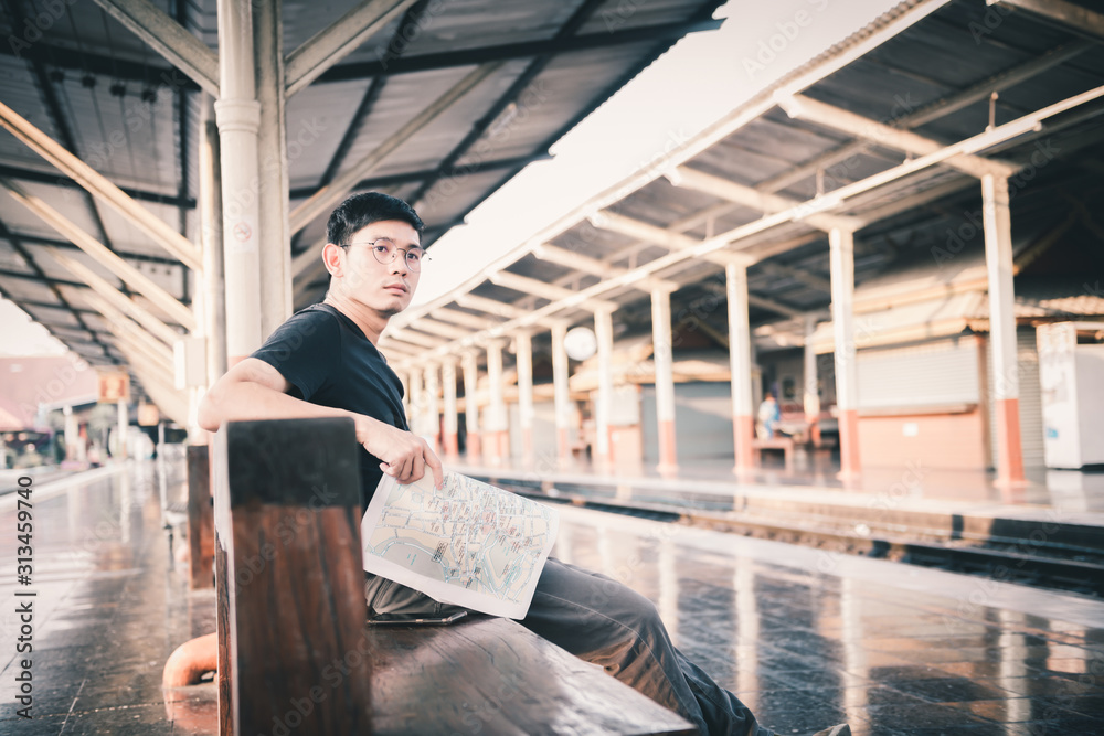 An Asian man sat and looked at the map. Luggage at the train station Tourism and travel concepts