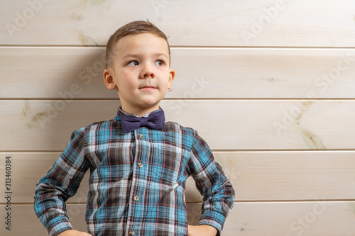 Bild auf Leinwand A 4 years old boy in a blue clerical shirt is crying on a light wooden background