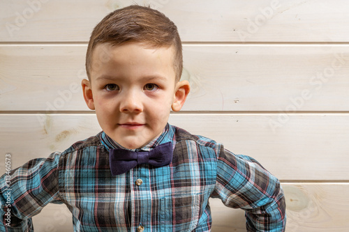 Foto A 4 years old boy in a blue clerical shirt is crying on a light wooden background