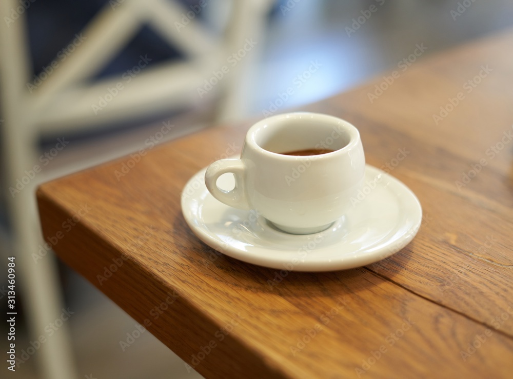 Fototapeta premium Espresso in white cup on wooden table in cafe.