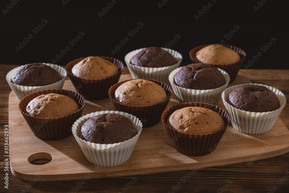 Cupcake. Tasty food cake. Chocolate muffins sprinkle with powdered sugar. Bakery products on black background. Black and white, light and shadow Cupcake. Tasty food cake. Chocolate muffins sprinkle with powdered sugar. Bakery products on black background. Black and white, light and shadow
