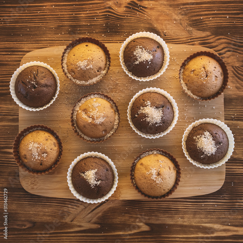 Cupcake. Tasty food cake. Chocolate muffins sprinkle with powdered sugar. Bakery products on wooden background. Black and white, light and shadow