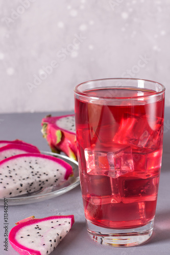 Glass of mango dragonfruit refresher drink on grey table with ice cubes. Copy space.